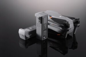 A DJI Air 3 drone placed on a reflective surface, accompanied by two intelligent flight batteries, one standing upright and the other lying flat, showcasing their design and labeling.
