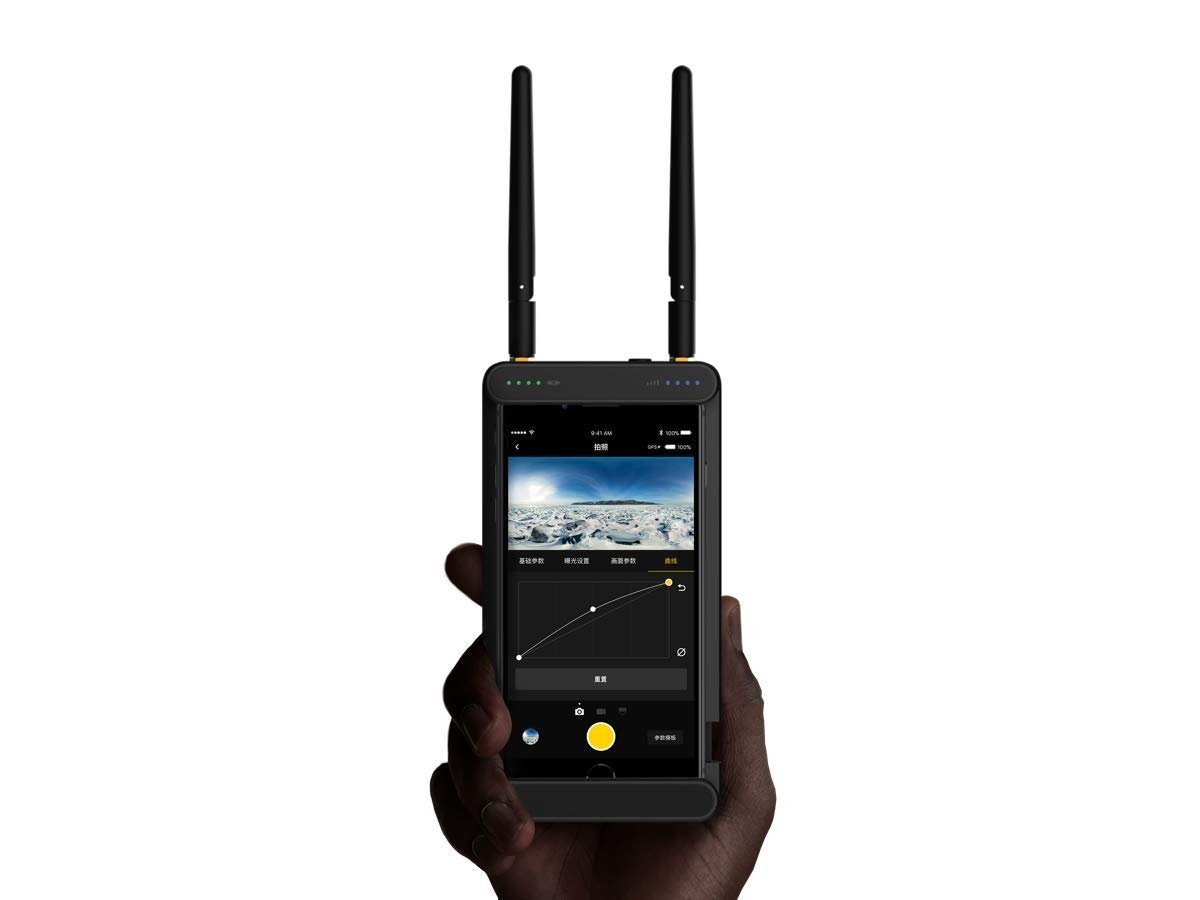 A hand holding a rugged handheld remote controller of Insta360 Pro 2 with a touchscreen display, dual antennas, and an interface showing a live camera feed with image adjustment settings.